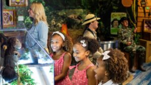 Three children smiling as they look at a small ape figurine in an exhibit at Ripley's Believe it or Not
